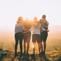 Picture of adults, during a sunset, holding hands with their backs towards the camera.
